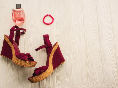 Stylish wedge shoes burgundy bracelet perfume bottle. Summer background mockup text. pattern top view above white wooden background. Summer fashion accessories beach. Women Vacation top conceptの写真素材