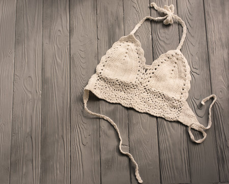 white knitted top woman trending two-piece swimsuit beach swimwear fashion sunglasses. Summer background template mockup space pattern composition sample text. Top view above grey wooden background.の写真素材