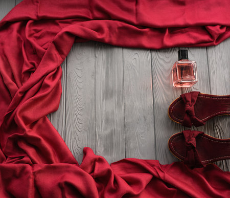 burgundy sandals wedge shawl shoes and bottle pink perfume. Summer background template mockup copy free space pattern colorful composition sample text. Top view above grey wooden background flat layの写真素材