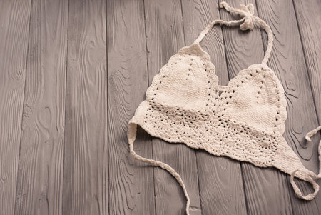 white knitted top woman trending two-piece swimsuit beach swimwear fashion sunglasses. Summer background template mockup space pattern composition sample text. Top view above grey wooden background.の写真素材