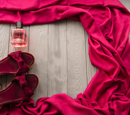 burgundy sandals wedge shawl shoes and bottle pink perfume. Summer background template mockup copy free space pattern colorful composition sample text. Top view above grey wooden background flat layの写真素材