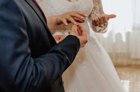 The bride and groom exchange rings. A man puts a wedding ring on a woman's hand. The girl put ring on man. official wedding ceremony in the registry officeの写真素材