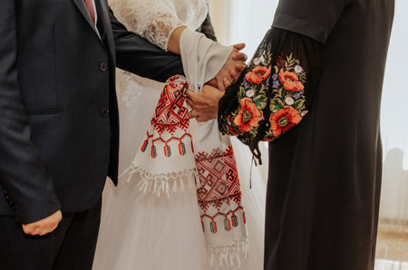 official wedding ceremony in the registry office. newlyweds are tied a white towel with a national ornament on their hands together. ukrainain tradition rushnykの写真素材