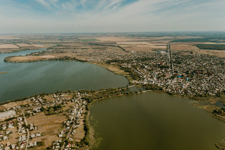 Rural summer sunset in Ukraine with Pivdennyi Buh river bridge dramatic colorful sky natural background, aerial view. Amazing landscape peaceful Ukraine. Beautiful top view village houses near riverの写真素材
