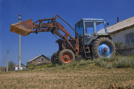 old excavator loader with raised bucket on the village road