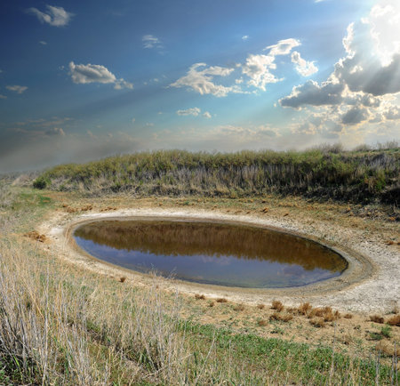 small round lake dries up in the dry semi-desert steppe with white salt residues along the coast