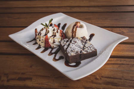 Chocolate brownies With whip cream and ice cream isolate on wood tableの写真素材