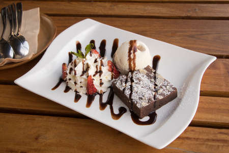 Brownie serve with Strawberry Whip Cream and Vanilla ice cream on plateの写真素材