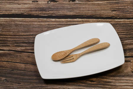 Wooden Spoon and fork on white plate on the wooden table. top viewの写真素材