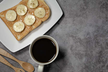 Coffee with butter bread with banana on concrete background. closeupの写真素材