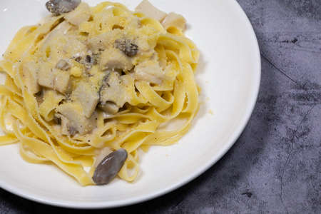 Close up on Tagliatelle with mushroom cream sauce on white plate on concrete backgroundの写真素材