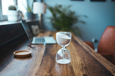 Hourglass on a wooden table in the office. Time management concept