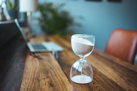 Hourglass on the table in the office. Time management concept.の写真素材