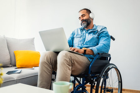 Elderly man in a wheelchair using a laptop at home.