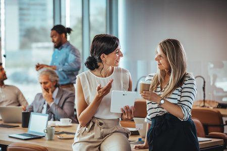 Two young businesswomen having a coffee break in the office during work.