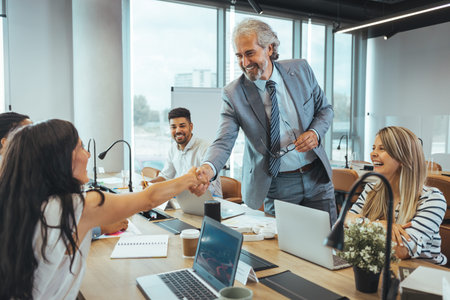 Happy business people shaking hands in a meeting at office. Successful business people concept.