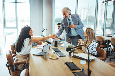 Business people shaking hands while sitting at the table in the office.の写真素材