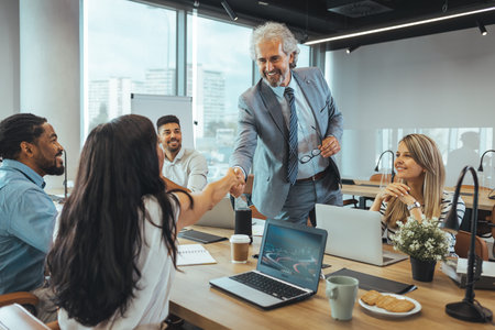 Business people shaking hands while working together in the office. Business people shaking hands, finishing up a meeting.の写真素材