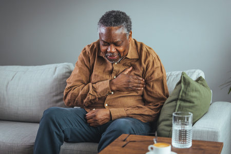Senior man suffering from chest pain, sitting on sofa at home.