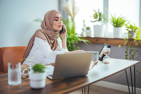 Portrait of muslim businesswoman talking on mobile phone while working in office