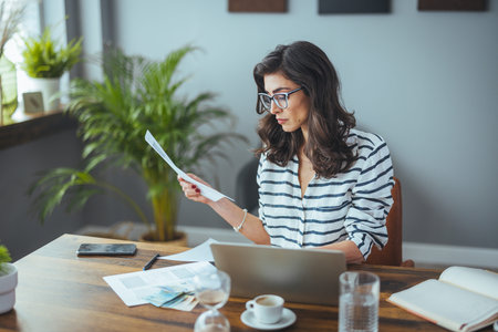 Young businesswoman working with documents while sitting at the table in office