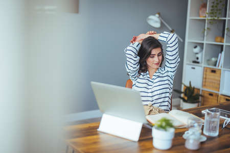 Portrait of a young woman sitting in front of laptop at homeの写真素材