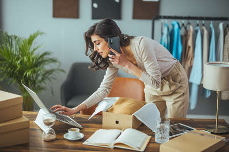 Businesswoman talking on mobile phone while working at her desk in officeの写真素材
