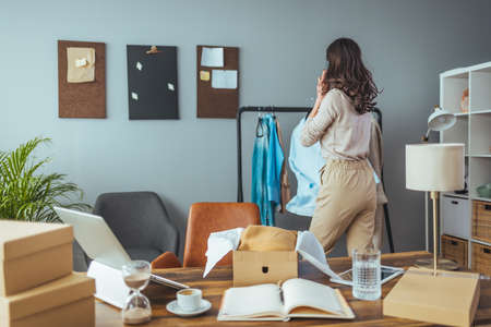 Young woman packing things for moving into new house, she is standing in front of the deskの写真素材