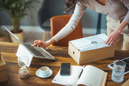 Cropped image of a young woman using a laptop while moving into a new office