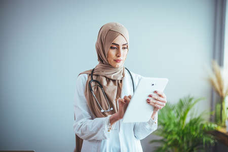 Portrait of muslim female doctor with stethoscope using digital tabletの写真素材