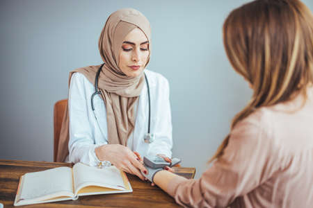 Muslim female doctor and patient discussing something while sitting at the table.の写真素材
