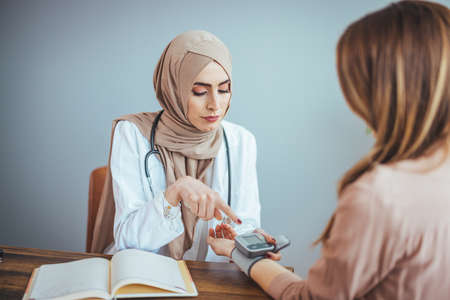 Muslim female doctor and patient discussing something while sitting at the table. Medicine and health care conceptの写真素材
