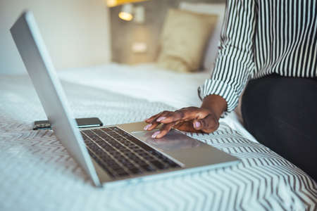 Cropped image of businesswoman using laptop on bed in hotel roomの写真素材