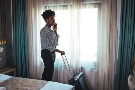 African american businesswoman talking on mobile phone in hotel room.の写真素材