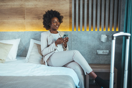 Beautiful african american woman using mobile phone in hotel room