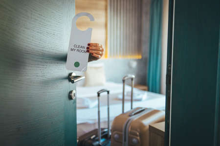 Close-up of female hand opening hotel room door with hotel room signの写真素材