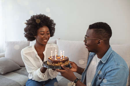 Happy african american couple celebrating birthday with cake and candles at homeの写真素材