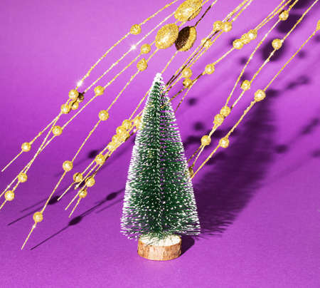 New Year's tree with golden decorations on a purple background. Minimal Christmas idea.の写真素材