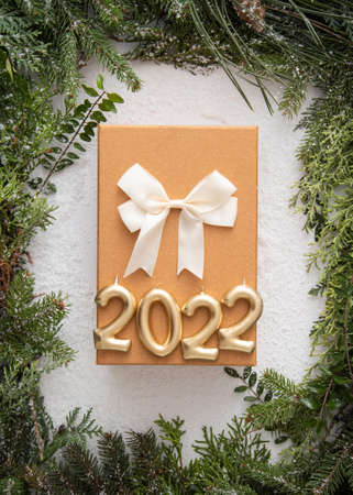 Homemade white copyspace and conifer brunches and cones in corners beautifuly arranged flat lay do it yourself minimalism natural art with snow and new year gift and gold candles 2022の写真素材