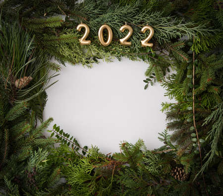 Homemade white copyspace and conifer brunches and cones in corners beautifuly arranged flat lay do it yourself minimalism natural art with 2022 gold candlesの写真素材