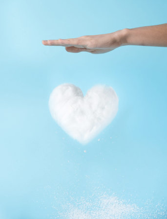 Levitating heart shaped cloud and white snowflakes falling from it in while hand energizes it blue...