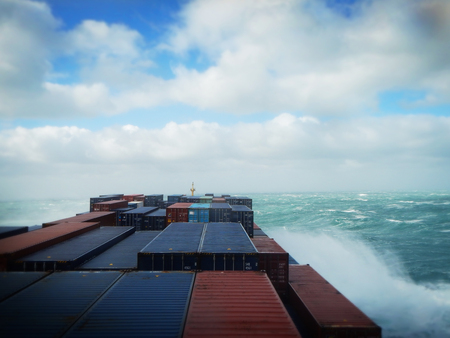 Container ship at rough sea, water spraying over cargo.の写真素材