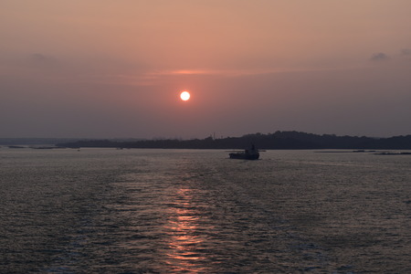 small cargo ship navigating in the river at the sunsetの写真素材