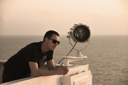 Man looking at the distance, posing on the navigating bridge deck near search light. Ideal concept for maritime publications.の写真素材