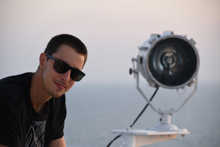 handsome man posing near the big search light on the navigating bridge deckの写真素材