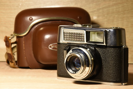 Old photo camera and protective case on wooden desk and wooden backgroundの写真素材
