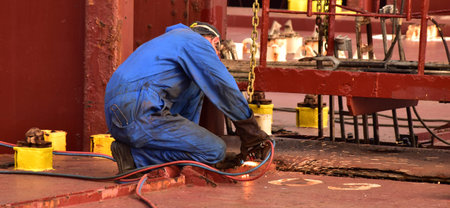 Ship's fitter making maintenance on top of hatch cover. Concept for maritime, engineering...