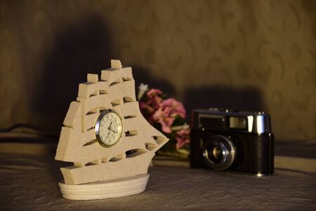 Model of a sailing ship with installed clock, vintage photocamera and bunch of colorful flowers. Concept for time passing, vintage and retro.の写真素材