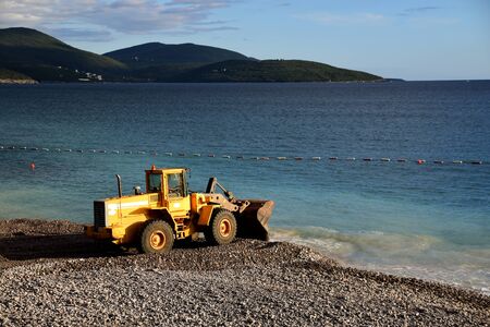 Digger throwing sand and rocks in the water to extend a beach. Water pollution. Photo taken in Lustica Bay, Montenegro.の写真素材