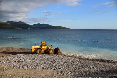 Digger throwing sand and rocks in the water to extend a beach. Water pollution. Photo taken in Lustica Bay, Montenegro.の写真素材